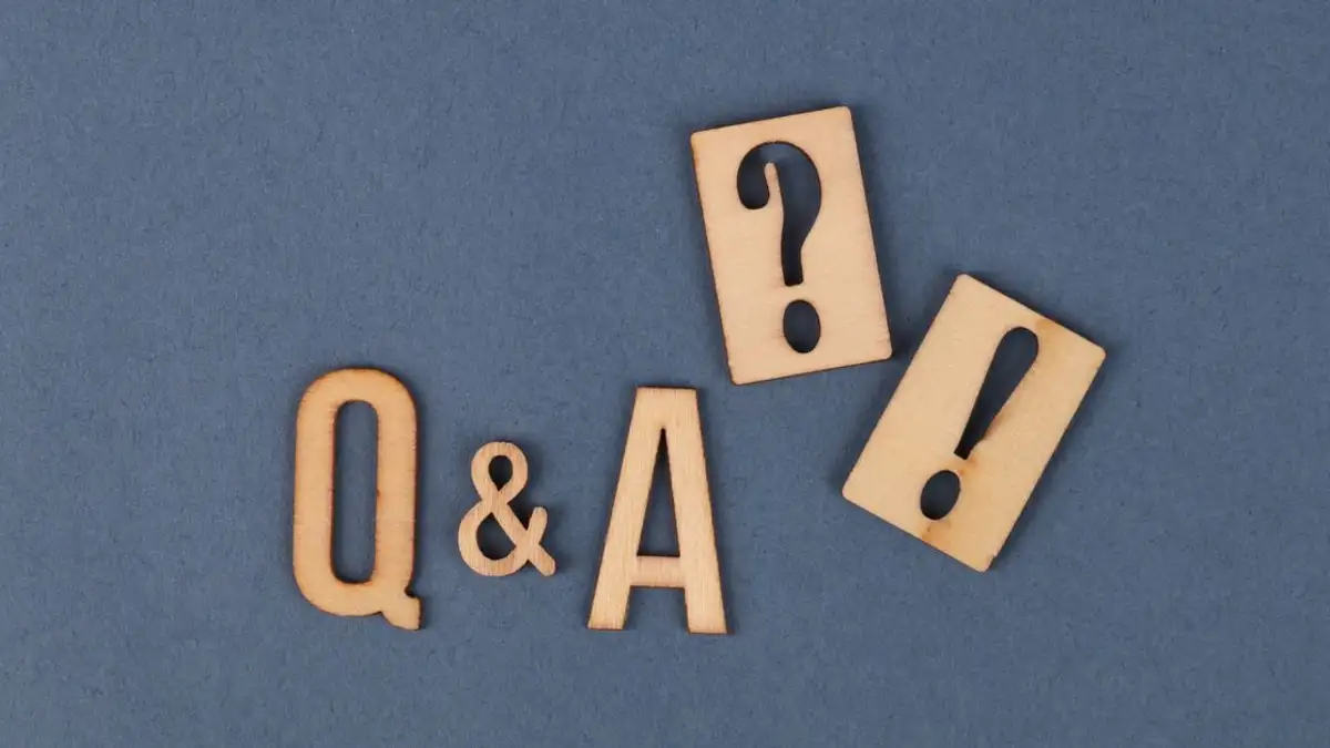 Tampilan datar huruf kayu Q&A dengan tanda baca di latar belakang abu-abu.