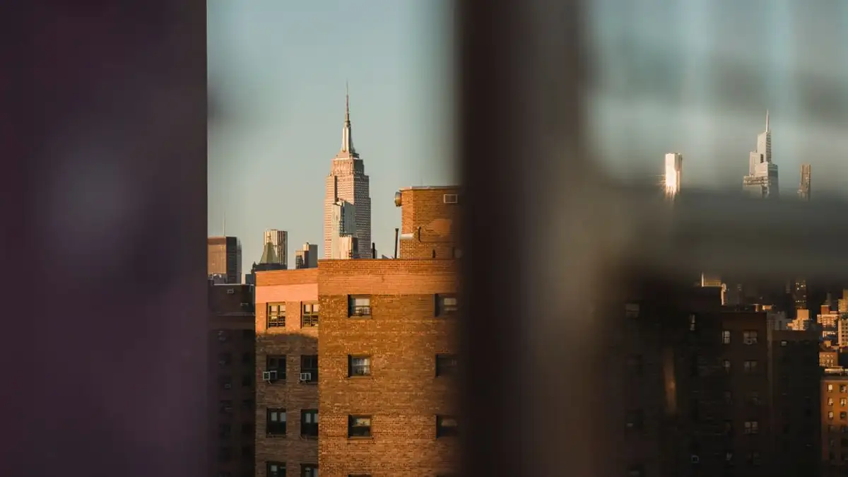 Pemandangan kota menampilkan Empire State Building melalui latar depan yang buram saat senja.