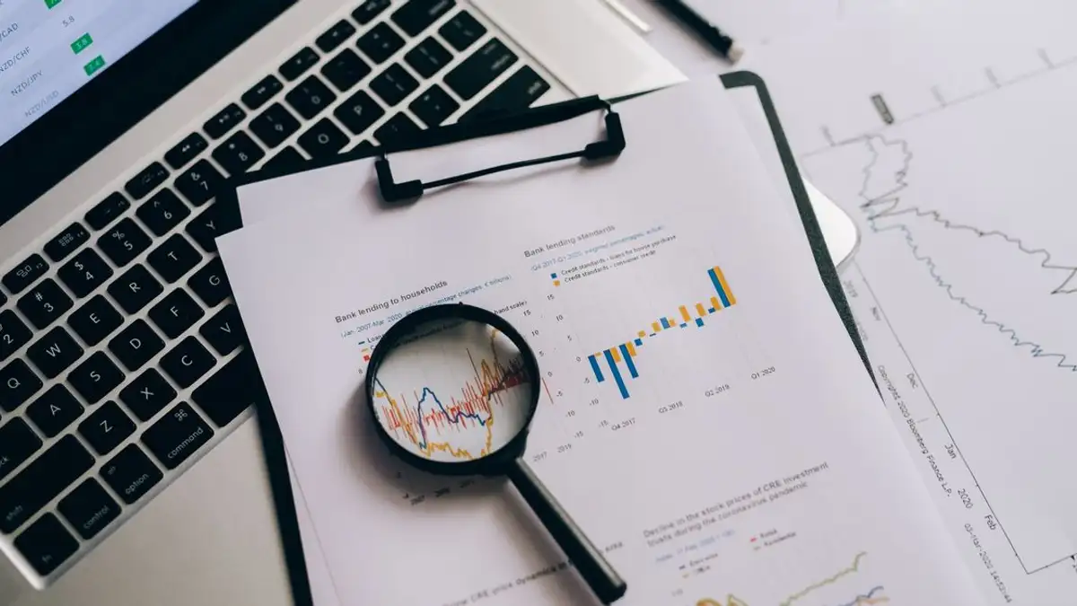 Tampilan dari atas grafik keuangan, laptop, dan kaca pembesar, ideal untuk tema analisis bisnis.