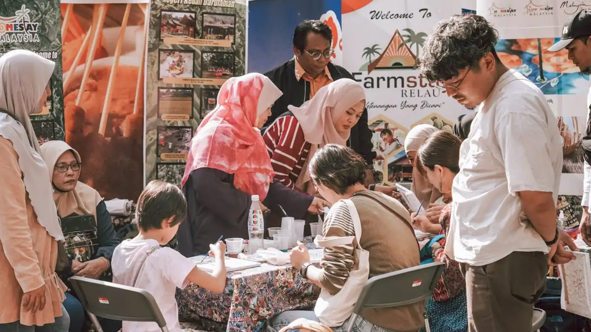Sekelompok orang yang beragam terlibat dalam kegiatan di stan festival budaya.