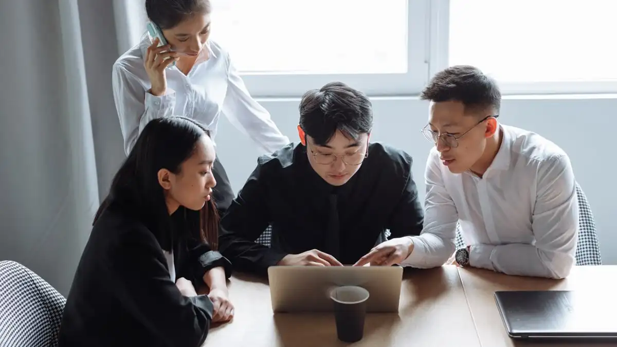 Tim bisnis sedang berdiskusi di lingkungan kantor dengan laptop dan semangat kerja sama.