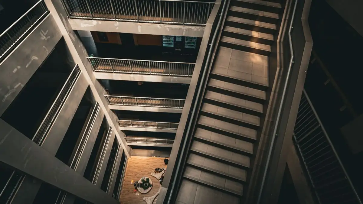 Pemandangan dramatis tangga dan atrium modern bertingkat dengan perspektif dari atas.