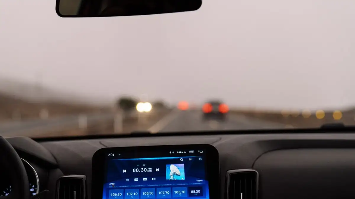Tampilan interior dashboard mobil di jalan terbuka pada siang hari. Sempurna untuk proyek bertema perjalanan.
